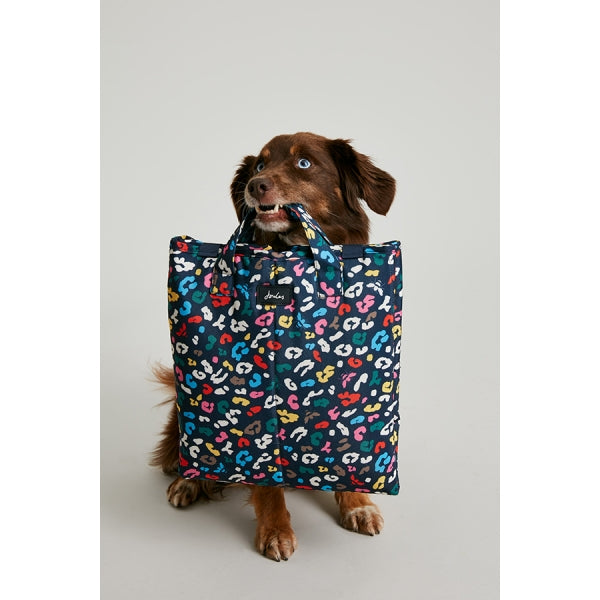 Dog holding Joules Multi-Bee Print Travel Mat folded away